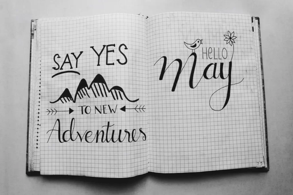 An open book with graph paper telling you to say yes to adventures and Hello May.