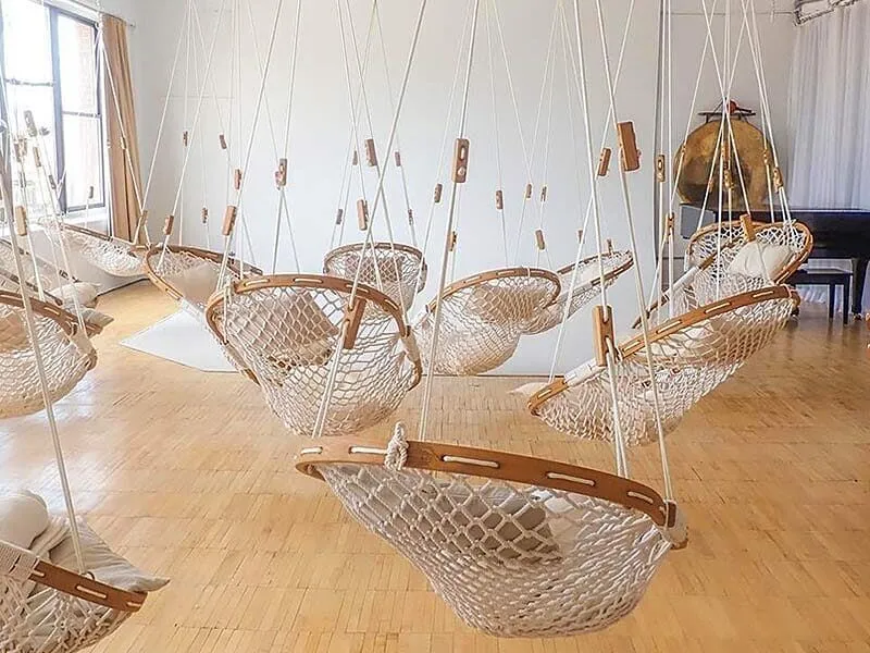 Fourteen Cobble Mountain Original Hammock Chairs with white pillows hanging randomly in a loft.