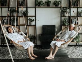 A man and a woman in bath robes relaxing in Cobble Mountain Hammock Chairs at a spa.