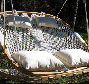 A Cobble Mountain Double Hammock Chair with white pillows and a Cobble Mountain Double Foothold hanging and tucked under it.
