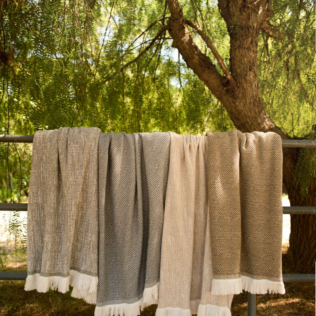 Sunbrella indoor outdoor throw blankets draped over a fence rail